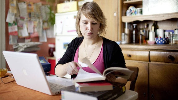 Studentin mit Laptop und Büchern in einer Küche