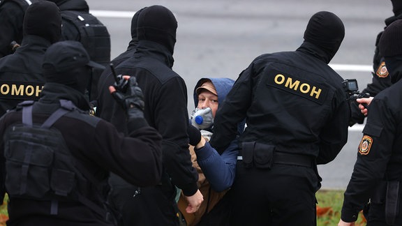 Polizisten tragen einen Mann von der Straße.