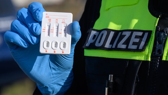 Ein Polizist zeigt einen positiven Drogen-Test auf THC (Cannabis) eines Autofahrers.