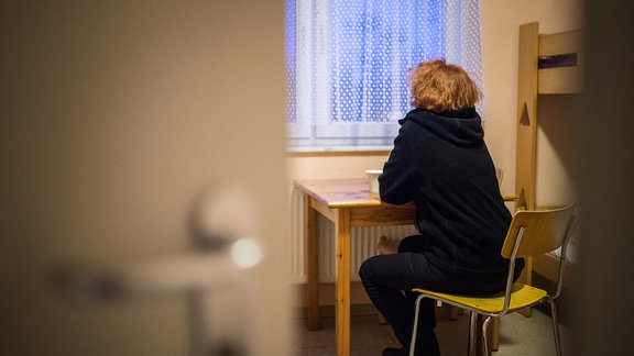 Eine Frau blickt in einem Frauenhaus aus dem Fenster