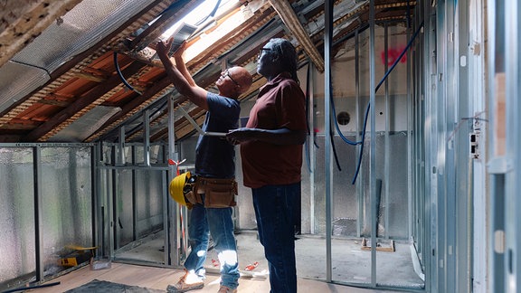 Zwei Menschen stehen auf einem Dachbodenbaustelle