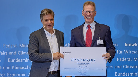 Robert Habeck (Bündnis 90/Die Grünen, l), Bundesminister für Wirtschaft und Klimaschutz, übergibt einen Klimaschutzvertrag an Hans-Peter Gai, Vorstandsmitglied der Südzucker AG.