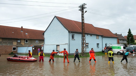 Kräfte von THW un DLRG stapeln Sandsäcke im Hochwasser