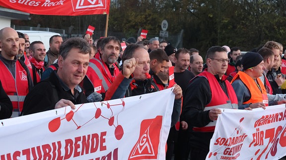 Arbeiter stehen bei einem Warnstreik der IG Metall am Eingang des Kaeser Werkes.