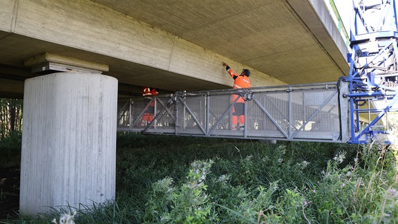 Stefan Ziegenhals (l-r) und Gunnar Wigger vom Straßenbauamt unterziehen die Brücke auf der B108 über die Radegast einer Prüfung.