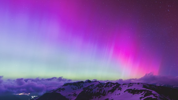 Polarlichter leuchten in der Nacht über Zell am See und der Großglockner Hochalpenstraße. 