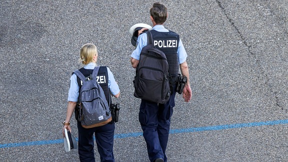 Schichtende für zwei Polizisten. Lässig marschieren sie mit privaten Rucksächen in Richtung Feierabend. 