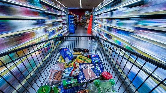 Ein Einkaufswagen mit Lebensmitteln wird am 30.11.2017 in Schwerin (Mecklenburg-Vorpommern) durch die Regalreihen in einem Supermarkt geschoben.