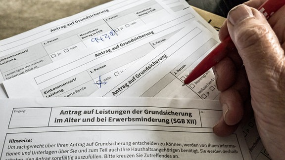 Ein Rentner füllt einen Antrag auf Grundsicherung im Alter aus.