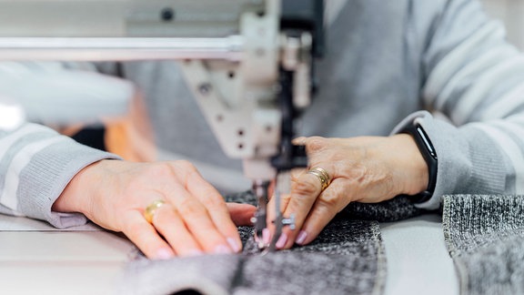 Ältere Handwerkerin an der Nähmaschine in der Werkstatt.