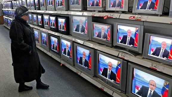 Eine Frau verfolgt in der Fernsehabteilung eines Kaufhauses in Moskau die jährlichen Live-Fragestunde an Präsident Putin im russischen Fernsehen