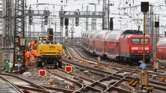 Gleisbauarbeiten am Hauptbahnhof Frankfurt mit Baggern und Gleisbauarbeitern neben einem vorbeifahrenden Regionalexpress, 2011