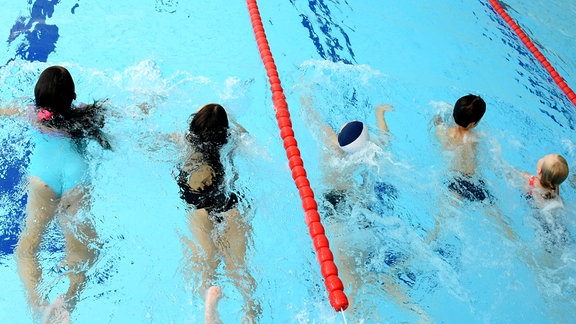 In einer Schwimmhalle nehmen Schülerinnen und Schüler während der Ferien am zusätzlich angebotenen Schwimmunterricht teil. 