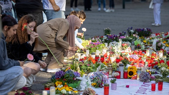 Menschen legen in der Nähe des Tatorts Blumen und Kerzen zum Gedenken der Opfer nieder. 