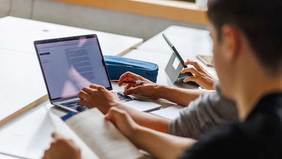 Schüler eines Gymnasiums sitzen vor einem Computer in der Schule.