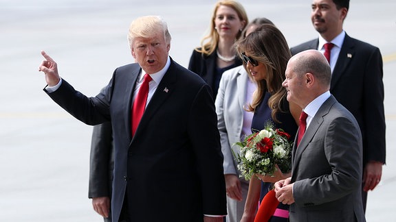 Hamburgs Erster Bürgermeister Olaf Scholz (r) begrüßt den Präsidenten der Vereinigten Staaten von Amerika (USA), Donald Trump (l), und seine Ehefrau Melania am 06.07.2017 nach ihrer Ankunft in Hamburg zum G20-Gipfel.