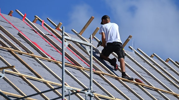 Ein Handwerker führt Arbeiten an einem Hausdach  durch.