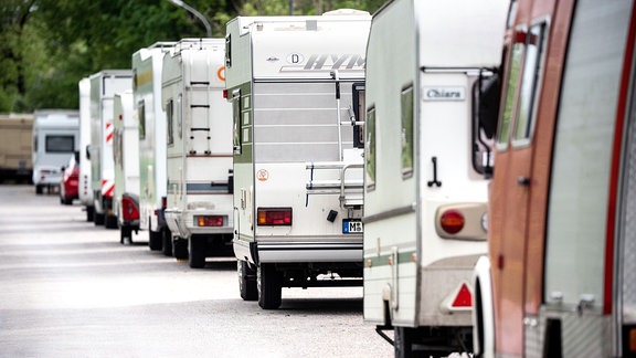 Geparkte Wohnmobile und Wohnanhänger stehen hintereinander in einer Straße