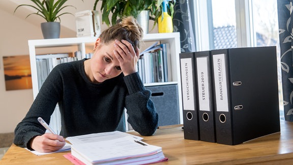 Frau sitzt nachdenklich am Schreibtisch