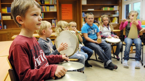 Schüler einer Grundschule spielen verschiedene Musikinstrumente im Unterricht