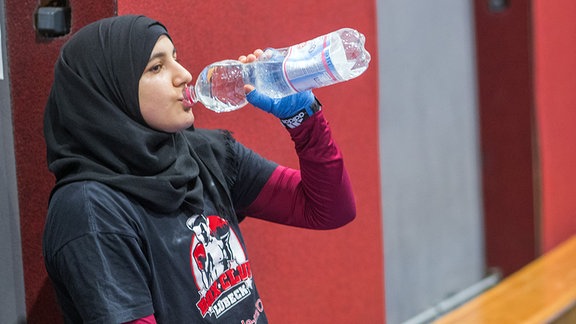 Eine Boxerin trinkt während des Trainings Wasser