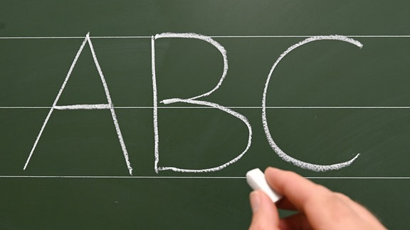 Die Buchstaben "A B C" sind in einer Grundschule mit Kreide an die Tafel geschrieben