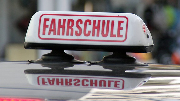 Ein Schild - Fahrschule - auf einem Autodach.