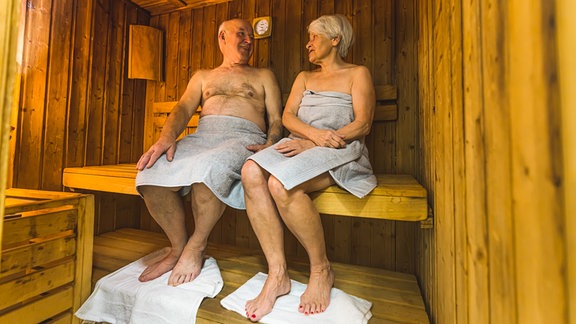 Ein Mann und eine Frau sitzen in einer Sauna.