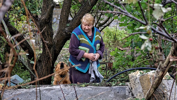 Eine Frau und ein Hund stehen in der Nähe eines Gebäudes, das durch den russischen Raketenangriff vom 18. Oktober 2024 beschädigt wurde.