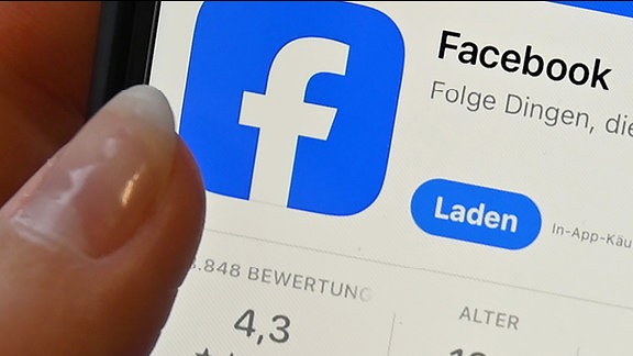 Symbolbild, Nahaufnahme eines Smartphone-Bildschirms. Ein Finger zeigt auf das Facebook-Logo.