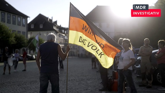 Ein Montagsdemonstrant von hinten mit einer Deutschland-Fahne mit Schriftzug "Wir sind das Volk"