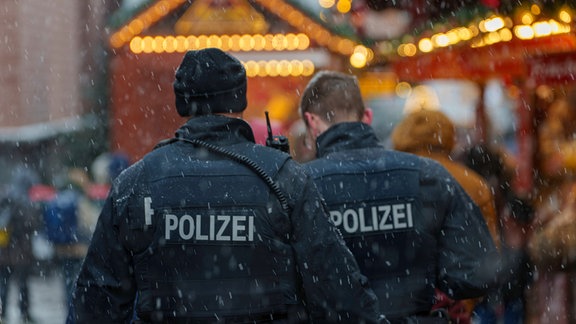 Zwei Polizisten gehen Streife auf dem Weihnachtsmarkt.