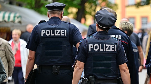 Polizisten laufen durch eine Innenstadt. 