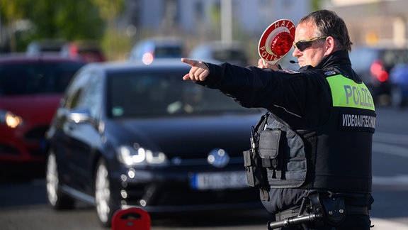 Ein Polizist winkt 2022 Autofahrer zu einer Kontrolle raus.