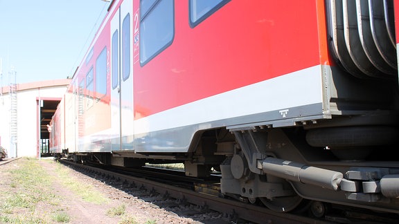 ein schwarz-gelber Schieber dockt unter der Achse einer S-Bahn an