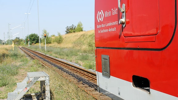 ein nasser Zug fährt auf rote Ampeln zu