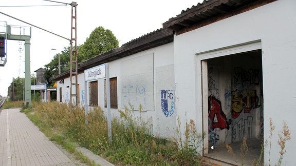 Ein Bahnsteig mit gemauertem Wartehäuschen, dessen Fenster mit Brettern vernagelt sind.