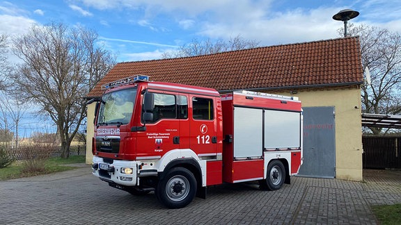 Ein Feuerwehrauto steht vor einem alten Gebäude.