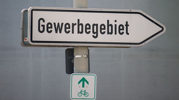 Ein Schild weist an einer Kreuzung den Weg zu einem Gewerbegebiet.