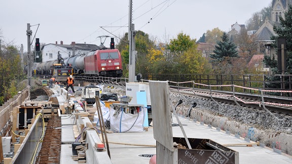 Ein Güterzug auf einer Brückenbaustelle der Saalebahn