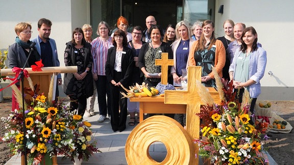 Viele Männer und Frauen stehen vor einem neuen Gebäude.