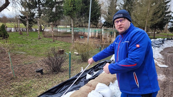 André Esnault zeigt mit einem Zollstock, wie hoch das Wasser während des Hochwassers am Helme-Deich stand