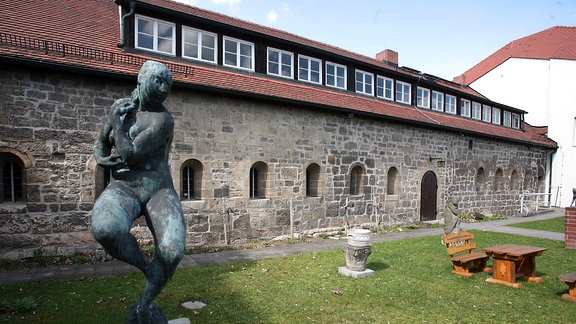 Das Romanische Haus, davor eine Wiese und eine weibliche Statue.