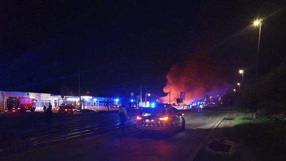 Blaulichter im Dunkeln vor einer großen Rauchsäule