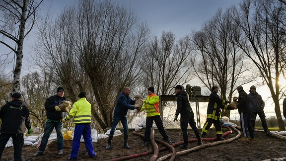 Feuerwehren und Einwohner errichten einen Sandsackwall als Hochwasserschutz entlang des Flusses Helme. 