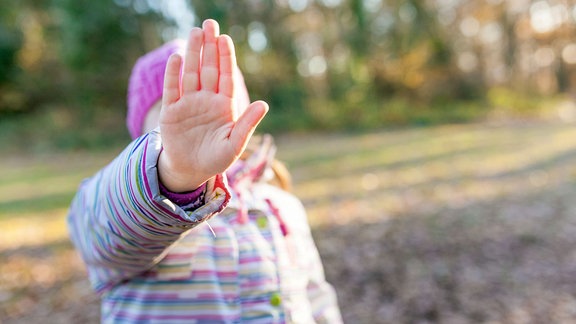 Kleines Mädchen zeigt Hand in Stopp-Geste.