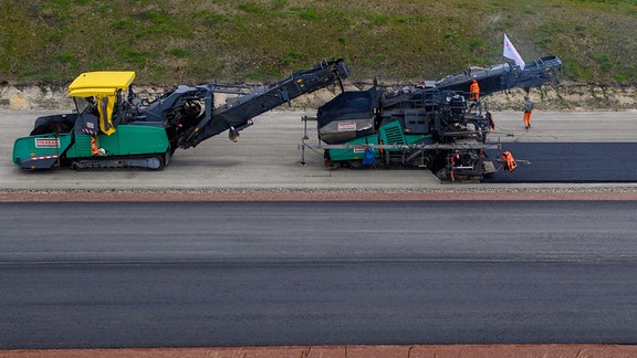 Arbeiter asphaltieren auf der A14-Baustelle die Fahrbahn der zuküftigen Autobahn. 