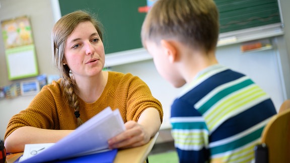 Eine Lehrerin, erklärt in einer Grundschule einem Schüler seinen Wochenplan