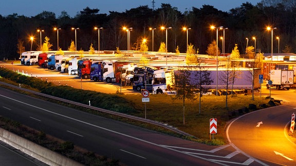 Ein Rastplatz mit LKWs an einer Autobahn.