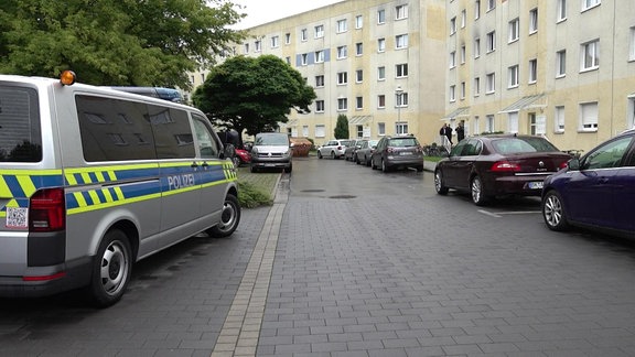 In einem Plattenbaugebiet parken zahlreiche Autos, ein Polizeiwagen steht auf der Straße